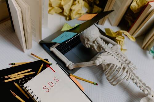 A toy skeleton lying on a laptop looking exhausted