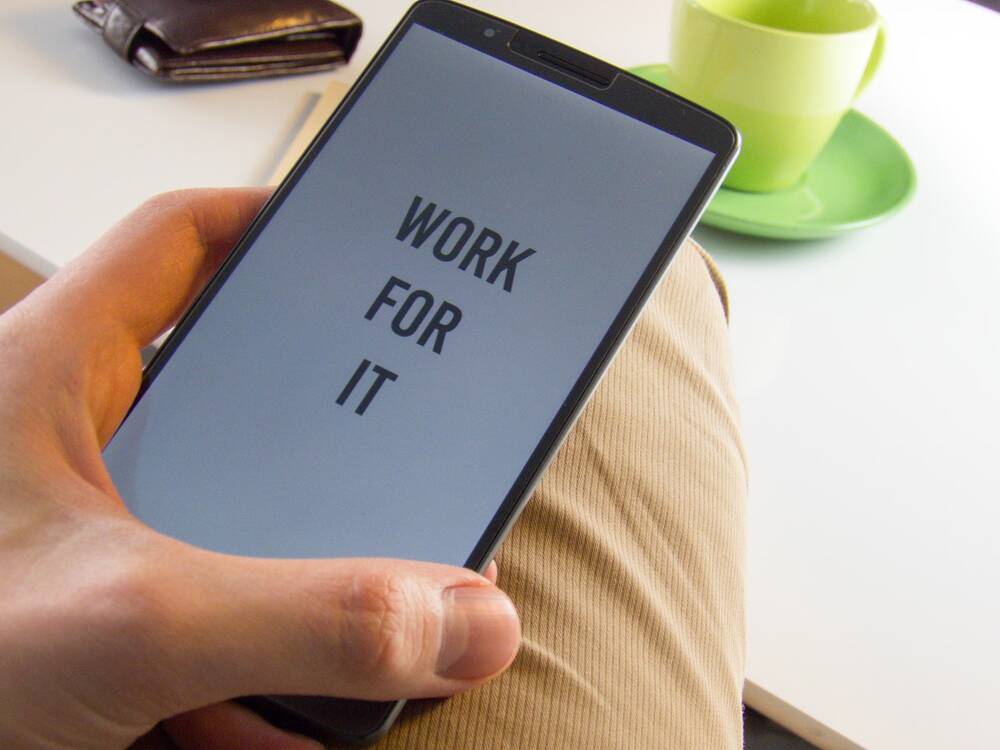 A hand holding phone with words 'WORK FOR IT'