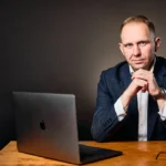 Jake Smolarek, architect of the 9-to-5 exit strategy, sits at his desk, demonstrating the clarity and control that lead to real freedom.