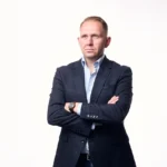 Jake Smolarek illustrating the founder to CEO transition, dressed in a blazer and looking thoughtfully into the distance to represent the strategic mindset required to scale.