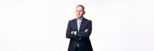 Jake Smolarek illustrating the founder to CEO transition, dressed in a blazer and looking thoughtfully into the distance to represent the strategic mindset required to scale.
