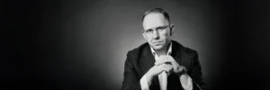 A black-and-white portrait of Jake Smolarek, a London-based high-performance coach and an expert in strategic time management