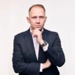 A professional portrait of Jake Smolarek, a high-performance coach in London, in a thoughtful, strategic pose.