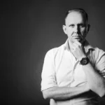 Black and white portrait of Jake Smolarek reflecting on achievement addiction and work obsession in high performers.